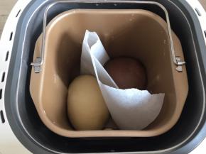 把面团分为等大的两份，其中一份加入7g可可粉，揉匀，面包机面桶内的搅拌刀取出，把两份面团用油纸隔开放入面包机桶内进行基础发酵