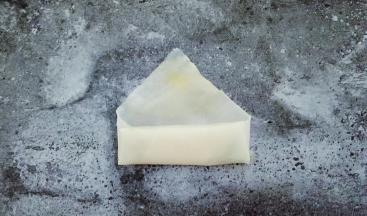 两边往中间折起来，继续卷，在三角上抹鸡蛋液