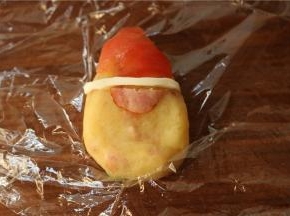 圣女果皮做了个帽子，鹌鹑蛋的蛋白做帽子边。剪半片香肠做大鼻子。