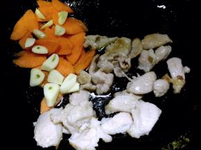 肉片变色后，放入蒜片和胡萝卜片翻炒几下