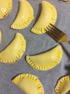 在派皮表面刷一层蛋黄液，再用餐叉在边缘按压紧实，一是这样烤的时候里面的蓝莓酱和巧克力就不会露出来了！再就是增加花纹，烤后中间更鼓，形状更漂亮！（也可以先用餐勺按压出花纹，再刷蛋液！）