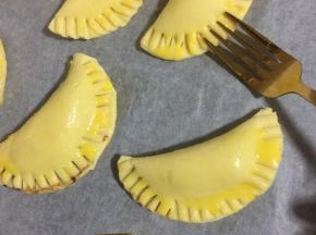 在派皮表面刷一层蛋黄液，再用餐叉在边缘按压紧实，一是这样烤的时候里面的蓝莓酱和巧克力就不会露出来了！再就是增加花纹，烤后中间更鼓，形状更漂亮！（也可以先用餐勺按压出花纹，再刷蛋液！）