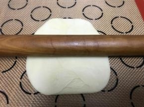 擀面杖擀成适中大小的剂子，擀法为：擀面杖放剂子中间，向上一下，向下一下，向左一下，向右一下，一圈下来如果剂子皮不够大，就再来一圈
