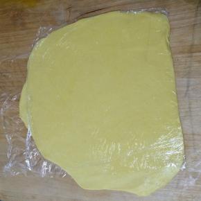 案板上铺一个保鲜袋，将冷藏好的面团放在上面，再铺上一个保鲜袋，将面团在两个保鲜袋之间擀开成为面片