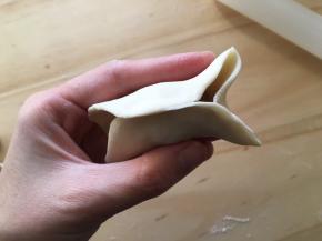 然后如图所示，两边从中间推进去，捏紧，然后凸出来那一小块再从凸出处往里按压捏紧