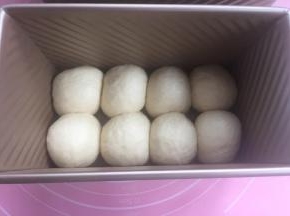 滚成圆团放入吐司盒（如图）。放入烤箱发酵。烤箱里放热水保湿