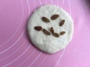 取一个擀成圆片，中间放几粒葡萄干