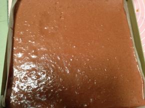 将面糊从高处倒入烤盘中，刮平表面，大力震几下，震出大的气泡