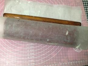 然后提起油纸用擀面杖辅助卷好