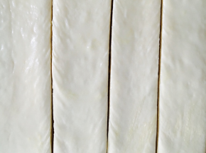 从底部捞出，排气擀平，涂上练乳。切成4等份