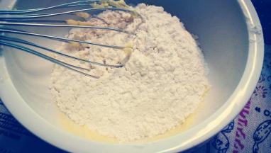 将黄油蛋液分装在两个盆中 倒入一半低筋粉搅拌