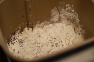 除黄油以外的所有材料放入面包机内（包括炒香的亚麻籽），启动和面程序，面团揉至八分时放入黄油揉至扩展，总时间20分钟