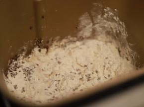 除黄油以外的所有材料放入面包机内（包括炒香的亚麻籽），启动和面程序，面团揉至八分时放入黄油揉至扩展，总时间20分钟