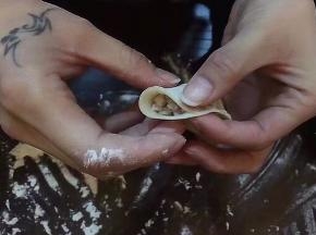 饺子皮平放手板心，右手食指和拇指在中心线捏一下，捏紧。。