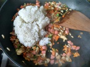 将米饭倒入锅中，将米饭炒散。