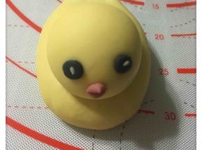 用竹碳粉、红曲粉少许和白面团调成黑色和红色，竹碳粉调成的黑面团做眼睛，红曲粉面团做嘴巴。眼睛搓成圆形，上面放一颗白芝麻。嘴巴切成菱形，同样需沾少许水以便黏牢，如图所示。