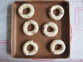 将贝果放在烤盘中，盖上保鲜膜，发酵30分钟