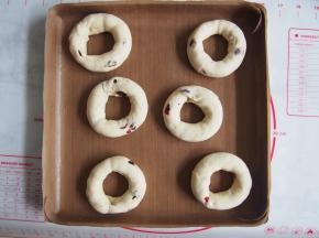 将贝果放在烤盘中，盖上保鲜膜，发酵30分钟