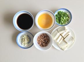肉末先加一点生粉、生抽腌制10分钟，然后下锅炒熟盛出备用，豆腐切片，香葱切段，大蒜切末，鸡蛋加一点点盐打散，生抽、老抽、蚝油倒入碗内，加一小碗高汤或者清水调匀