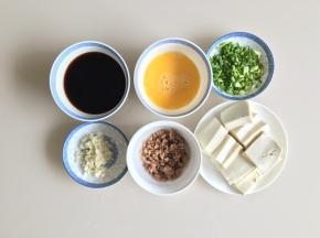 肉末先加一点生粉、生抽腌制10分钟，然后下锅炒熟盛出备用，豆腐切片，香葱切段，大蒜切末，鸡蛋加一点点盐打散，生抽、老抽、蚝油倒入碗内，加一小碗高汤或者清水调匀