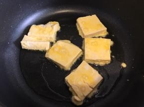 豆腐先在玉米淀粉里两面裹上一层淀粉，然后再鸡蛋液里滚一圈，锅内下食用油，热稍微热后下豆腐煎