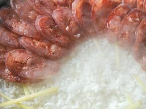 米煮至八成熟的时候，撒上姜丝，然后铺上香肠，盖上盖子小火焖7分钟。