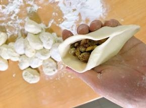 对折，一头捏起，捏到接近中间。开口部分，向中间推，捏住。