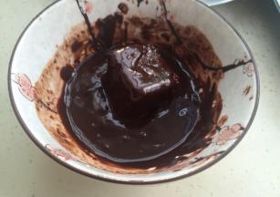 100克巧克力在35克牛奶里溶化。把蛋糕块放入裹上巧克力酱