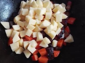 放入葱蒜、胡萝卜丁翻炒，几分钟后放入土豆丁炒匀；不用放盐调味，腊肉比较咸