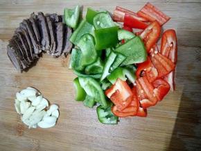 将卤好的牛肉切片，双椒切大块，蒜瓣切片。