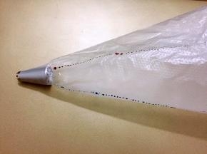 裱花袋装入裱花嘴，再用翻糖笔沾上色素在裱花袋里画上直线，如图