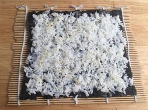 把一半量的米饭摊开，撒白芝麻