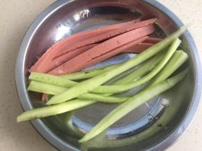米饭在电饭煲里煮熟，把青瓜去皮切成条，火腿肠也切条