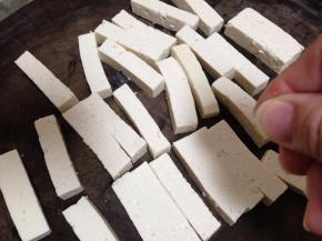 北豆腐切成长约5cm、宽约1cm、厚约1cm的条，在豆腐表面撒少许的盐腌10分钟（不要多，用两指捏点就行）
