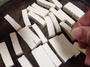 北豆腐切成长约5cm、宽约1cm、厚约1cm的条，在豆腐表面撒少许的盐腌10分钟（不要多，用两指捏点就行）
