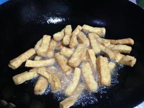 炒汁的同时，锅内的油再次烧热至7、8成热，倒入豆腐条炸至表面深黄时捞出（一定要大火炸至表面酥脆）