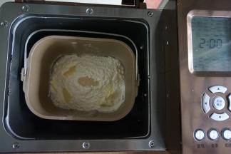 加入奶粉、面粉和切成小块的黄油，在面粉顶端加入酵母