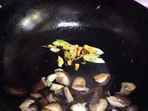 把香菇片拨到一边，小火下入葱、蒜、油豆豉炒出香味，烹料酒去腥