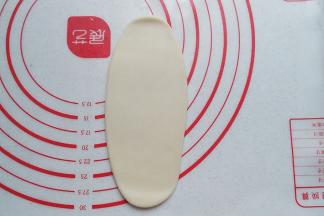 取一份静置好的面团擀开，擀成长随圆形，尽量稍长些，起酥效果也会更好些；