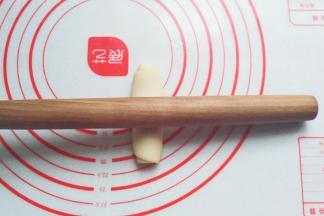 静置好的面团先稍压扁，然后把擀面杖放在面团中间，分别向两头擀开；