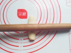 静置好的面团先稍压扁，然后把擀面杖放在面团中间，分别向两头擀开；