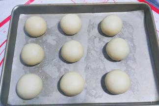 包好后收口朝下，摆入烤盘，用手压扁，把馅料尽量向边围推均匀；