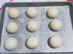 包好后收口朝下，摆入烤盘，用手压扁，把馅料尽量向边围推均匀；
