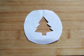 然后找张小纸片画上圣诞树轮廓，并用剪刀在中间剪去多余部分，便得到漏空圣诞树小图形；