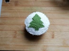 然后揭去纸片，一棵小巧的圣诞树就出来了，最后随意装饰几颗彩色糖珠，可爱的圣诞树纸杯蛋糕就完成啦！