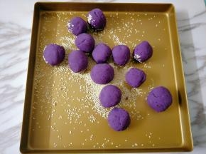 烤盘撒适量芝麻，放入紫薯球不停翻滚
