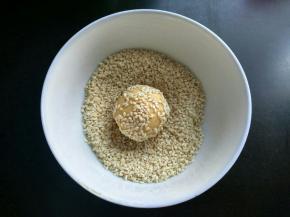 红薯球蘸一点清水，在芝麻里面滚一滚，沾上芝麻。