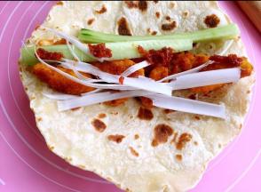 在饼皮上放鸡肉，大葱、青瓜，调味酱。