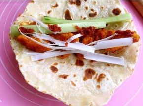 在饼皮上放鸡肉，大葱、青瓜，调味酱。