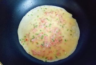 平底锅加热，刷上一层食用油。热锅中，盛两勺面糊，拿起平底锅摇晃一圈，再用勺子底部将面糊摊平。 小火煎至鸡蛋饼表面的蛋液凝固即可。